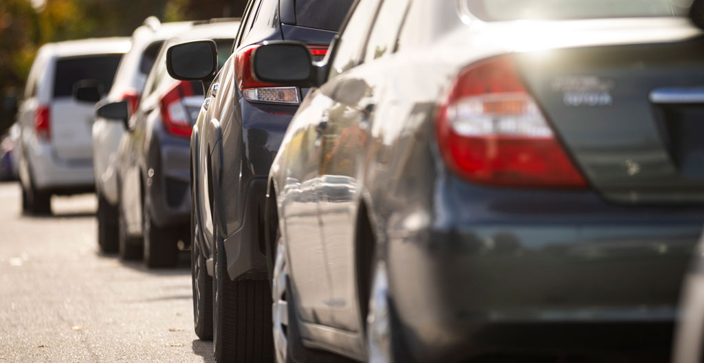 Stationnement résidentiel québécois avec différents types de véhicules reflétant des usages variés